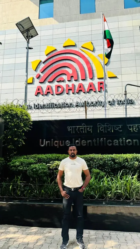 Sanjeewa standing outside a building displaying the Aadhaar name and logo.